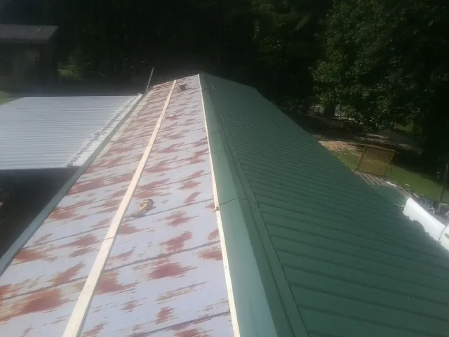 Old rusted panels beside newly installed green metal roofing — Wind Damage Roof Repair by Roofing Brothers in Big Bear City