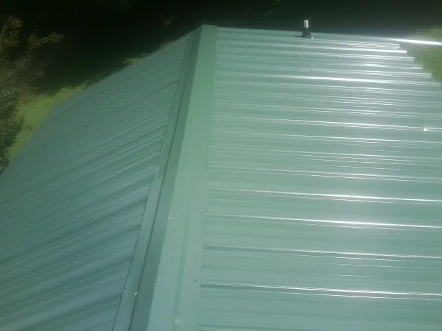 New green metal panels meeting at the ridge of a roof — Flat Roof Repair work by our crew in Big Bear City