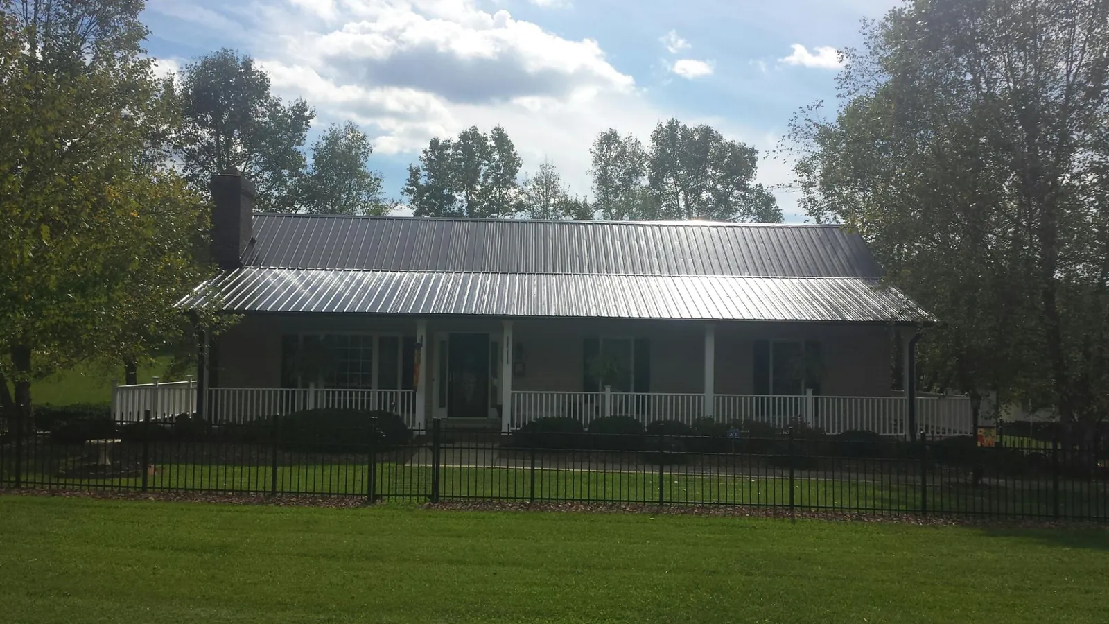 Gray metal roof on a brick ranch with a full width front porch — Gutter Guard Installation work by our crew in Big Bear City