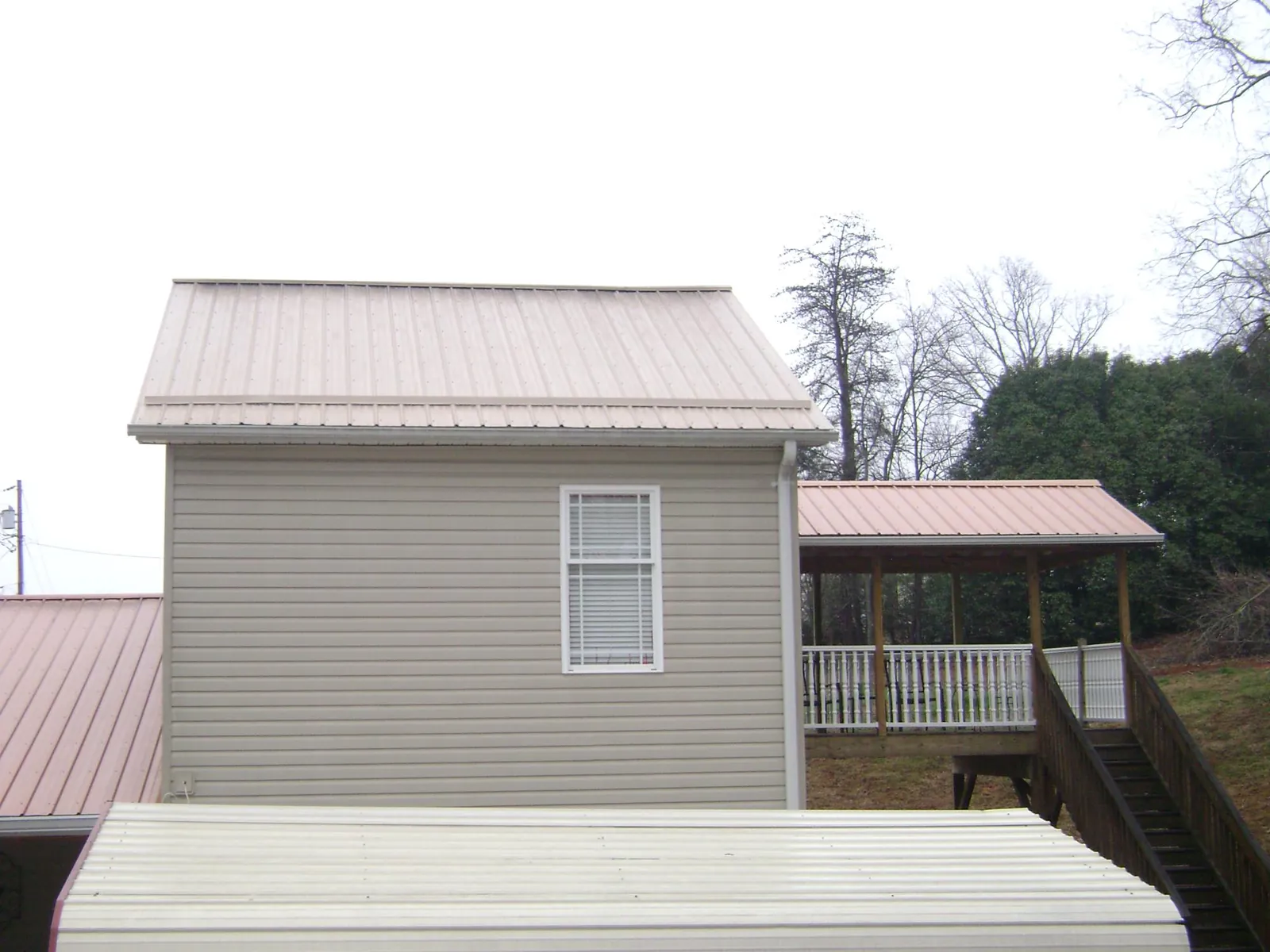 Tan metal roofs on a two story addition and attached porch, from a Roof Replacement job in Big Bear City