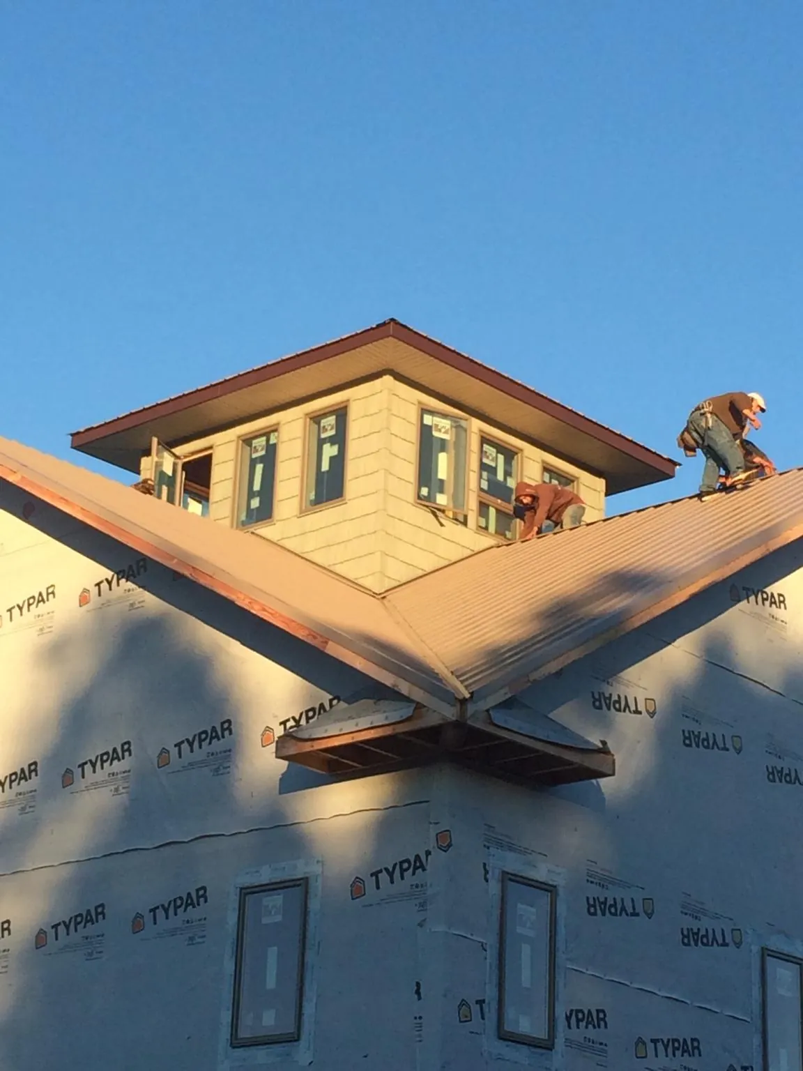 Roofers working around a rooftop cupola on a new metal roof at sunset — Roof Waterproofing in Big Bear City by Roofing Brothers